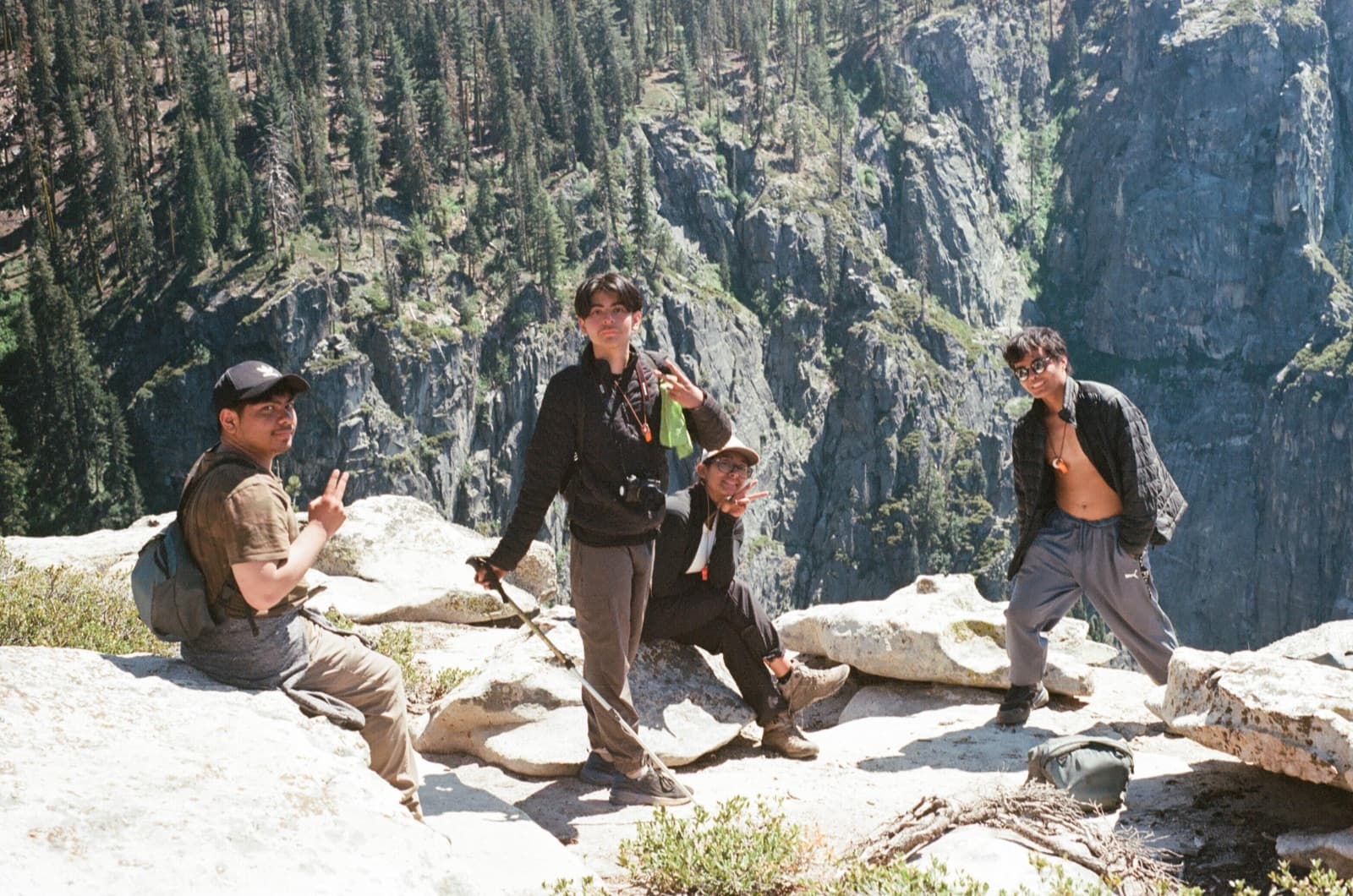Four Druids students rest on a granite overlook high above a Yosemite canyon, full backpacks beside them